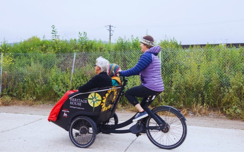 Cycling Without Age trishaw carrying two elderly people along the waterfront