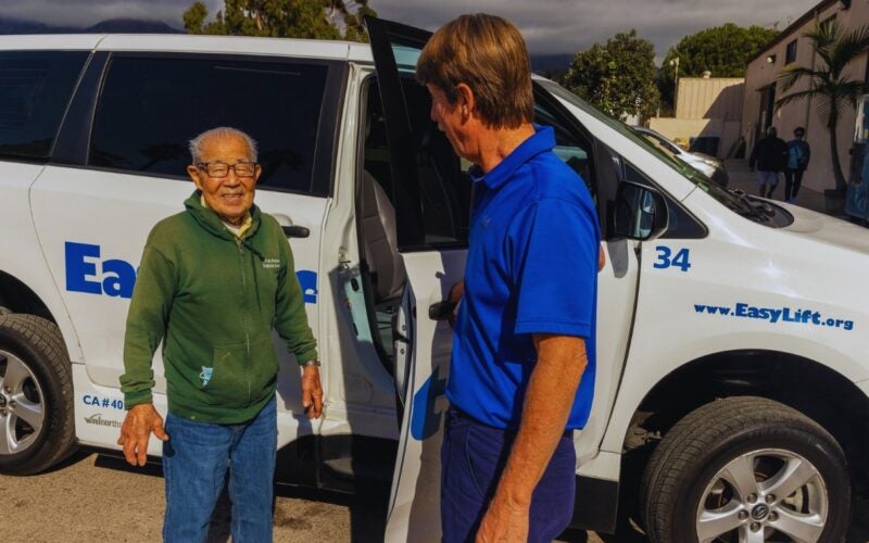 EasyLyft driver talking to a passenger and holding door open