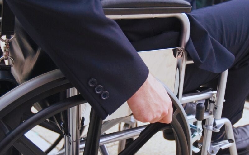 Person in suit grabbing wheel of a wheelchair