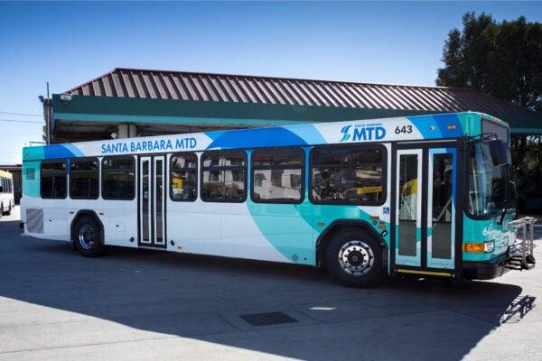 Santa Barbara MTD city bus parked at a transit yard under a clear blue sky.
